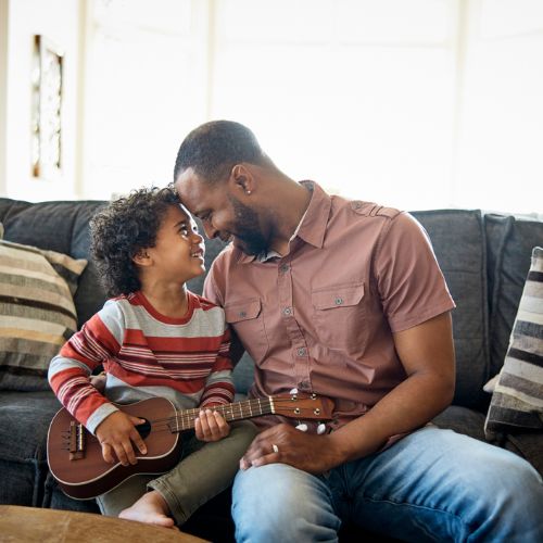 man with child, who is holding a ukulele 